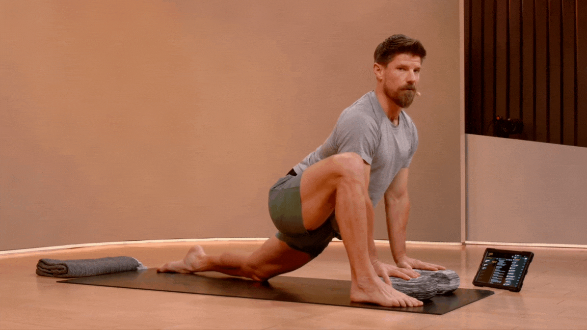 Peloton instructor Denis Morton demonstrates modified Lizard Pose in yoga with the rear knee on the floor and hands on yoga blocks