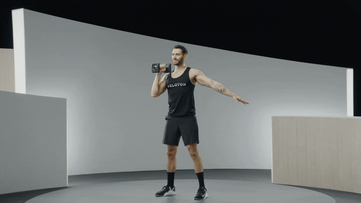 Peloton instructor Matty Maggiacomo demonstrates single-arm dumbbell thrusters