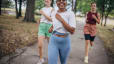 A group of three friends happily running together outside in a park. Learn about intrinsic vs. extrinsic motivation here.