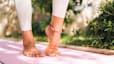 Close up shot of bare feet as someone does foot stretches on a yoga mat