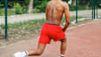 Man doing Bulgarian split squats on a park bench during a no-equipment full body workout.