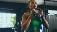 Woman holding a kettlebell in front of her chest while doing kettlebell arm exercises in a gym.