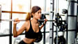 Woman does a back squat with barbell at gym