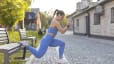 Woman does a split squat on a bench outdoors 