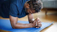 Man in a blue shirt doing a forearm plank during a bodyweight workout at home