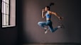 Woman does a jumping exercise indoors, an explosive exercise