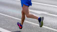 A close-up view of a runner's legs running on an outdoor paved road.