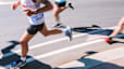 A close-up photo of runners' lower bodies quickly running a marathon.