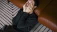 A man leaning against a couch at home while rubbing his eyes as he deals with the Sunday scaries.