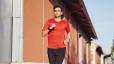 Man wearing red shirt running down street