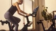 Woman cycles at home on Peloton Bike.