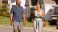 A couple happily walking after eating in their neighborhood.