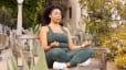 Woman meditating outside on a park bench in workout clothes