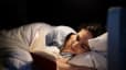 A woman reading a book while lying in bed at night as part of her bedtime routine.