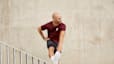 Man in workout gear stretching his hamstring on a handrail