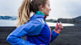 A side-view photo of a woman running outside on a chilly day.
