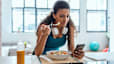 A woman eating after a workout and looking at her phone.