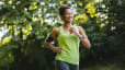 A woman happily embracing a beginner's mindset while going for a jog in nature.