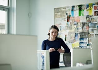 A woman standing in front of a vision board in her office.