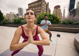 2 exerciser engaged in a yoga class on a rooftop overlooking the city of New York