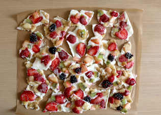 A tray of vegan Greek yogurt bark with various fruits in it like strawberry, banana, kiwi, blackberries, and raspberries. It's a high-protein vegan snack.