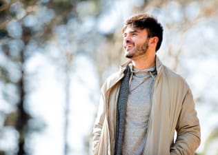 A smiling man going on a walk outside, which is a great self-care idea.