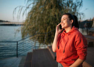 A woman habit stacking by talking on the phone and walking outside at the same time.