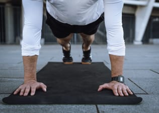 Man in high plank pose on black workout mat 