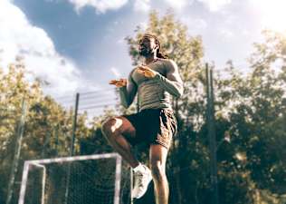 Man doing high knees warm-up exercise during an outdoor workout.