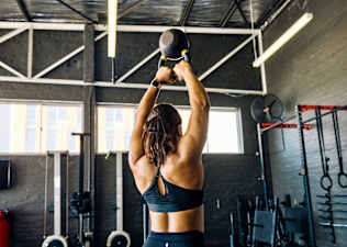 A woman doing kettlebell back exercises in a gym.