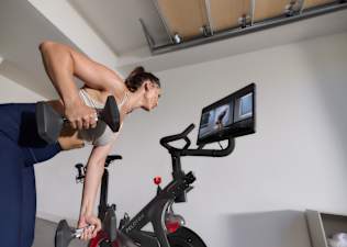 Woman doing a strength workout and taking advantage of all the strength training features on the Peloton Cross Training Bike+ powered by Peloton IQ.