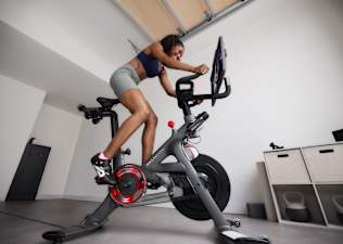 Woman doing bike sprints on a Peloton Bike during a home cycling workout.