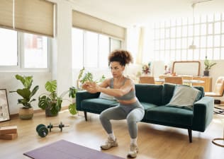 Young woman does squats in living room 