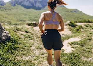 Woman running up a mountain wondering whether or not running is a full body workout.