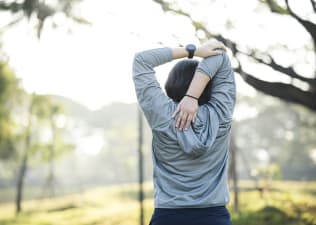 Woman does tricep stretch outdoors