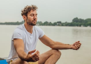 A man meditating outside to strengthen his mind-body connection.