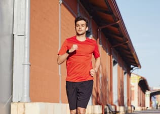 Man wearing red shirt running down street