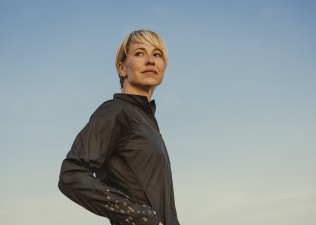 A woman looking self-confident as she stares over her shoulder while standing outside.