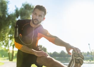 A man stretching his leg outdoors before he works out twice a day.