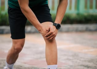 Is running bad for your knees? Man holds his knee while pausing during a run