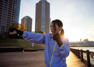 Woman shadowboxes outside on the river, what is shadowboxing