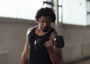 A man lifting dumbbells in a modern gym to build muscle.