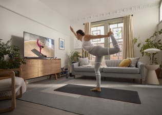 Woman practices a dancer pose at home. 