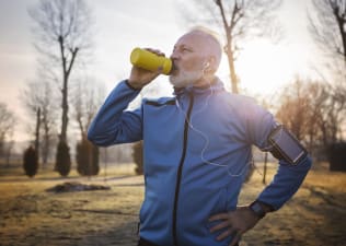 Man drinks from his water bottle while running