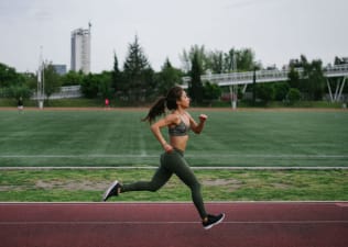 Woman runs outside on a track, how to increase vo2 max