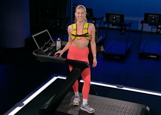 Peloton instructor Rebecca Kennedy poses on the Peloton Tread+ before teaching a weighted vest walking class.