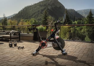 A couple working out on Peloton bikes in a hotel fitness center