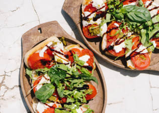 A close-up photo of two plates of caprese salad on bread.