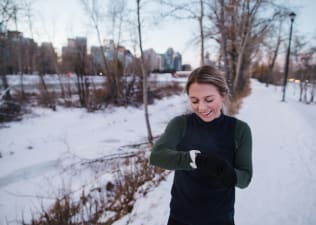 Woman checks her watch on a cold-weather run