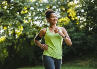 A woman happily embracing a beginner's mindset while going for a jog in nature.